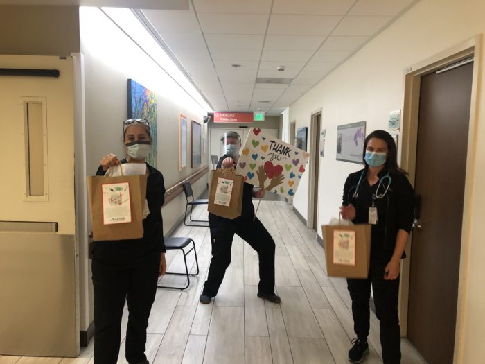 3 nurses holding PME care packages in hospital hall